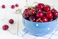 Red cherries in bowl on white wooden background on blue towel Royalty Free Stock Photo