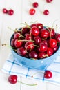 Red cherries in bowl on white wooden background on blue towel Royalty Free Stock Photo