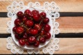 Red cherries on a lacy napkin on wooden background, a top view Royalty Free Stock Photo