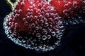 Red cherries in a mineral water with lots of bubbles on a black background, close up Royalty Free Stock Photo