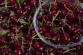 Red cherries in a transparent glass bowl on a wooden background, with green leaves of a cherry tree. Summer berries. Yummy Royalty Free Stock Photo