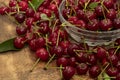 Red cherries in a transparent glass bowl on a wooden background, with green leaves of a cherry tree. Summer berries. Yummy Royalty Free Stock Photo