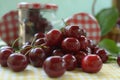 Red cherries on yellow tablecloth and red cap of jars Royalty Free Stock Photo