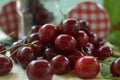 Red cherries on yellow tablecloth and red cap of jars Royalty Free Stock Photo