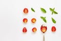 Red cherry tomato, green basil leaves and spoon on white background Royalty Free Stock Photo