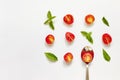 Red cherry tomato, green basil leaves and spoon on white background Royalty Free Stock Photo