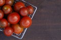Red cherry tomatoes in a metal shopping basket on a Garden wooden brown bench. Close-up, flat lay, top view, copy space