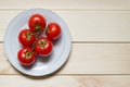 Red cherry tomatoes on plate on light wooden background with copy space Royalty Free Stock Photo