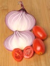 red cherry tomatoes and sliced red onion on bamboo slice board Royalty Free Stock Photo