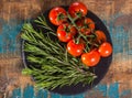 Red cherry tomatoes on vine and fresh green rosemary top view Royalty Free Stock Photo