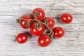 Red cherry tomatoes on withered branch on old wooden surface