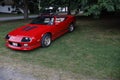 A Red Chevrolet Camaro IROC Cabriolet Resting on a Lush Green Lawn, with a Leafy Branch in the Corner