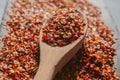 Red chili flakes. Close up view of heap of chili flakes on wooden spoon. Red cayenne pepper background. Royalty Free Stock Photo