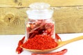 Red chili pepper powder in spoon with chili pepper in bottle