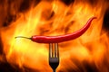 red chili pepper, pricked on a fork, on a background of burning fire, flames on a black background