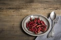 Red chili pepper on a vintage plate, antique silver spoon and fork, dried chillies on wooden background. Top view. Copy spase. Royalty Free Stock Photo