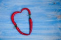 Red chili peppers arranged in a shape of heart on a wooden background