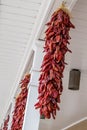 Red chili peppers hanging in the open air with white columns.
