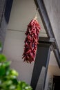 Red chili peppers hanging in the open air with black beams.