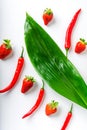 Red chili peppers and ripe strawberries and green leaves on a white background Royalty Free Stock Photo