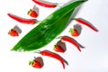 Red chili peppers and ripe strawberries and green leaves on a white background Royalty Free Stock Photo