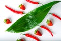 Red chili peppers and ripe strawberries and green leaves on a white background Royalty Free Stock Photo