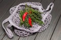 Red chili peppers and thyme twigs in natural reusable mesh bag