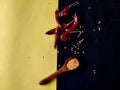 Red Chilli flakes in wooden spoon and red chillies on yellow and black background Royalty Free Stock Photo