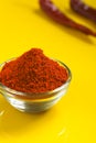 Red chilli powder in glass bowl on yellow background Royalty Free Stock Photo