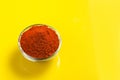 Red chilli powder in glass bowl on yellow background. top view Royalty Free Stock Photo