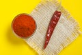 Red chilli powder in glass bowl on yellow background. top view Royalty Free Stock Photo