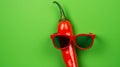Red chilli wearing sunglasses on green background Royalty Free Stock Photo