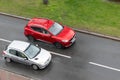 Red Chinese MG ZS crossover overtaking Peugeot 206 car in heavy rain on street Royalty Free Stock Photo