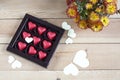 Red chocolate hearts in box and flowers on wooden table Royalty Free Stock Photo