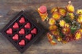 Red chocolate hearts in box and flowers on wooden table Royalty Free Stock Photo