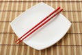 Red chopsticks and white dish on a bamboo napkin Royalty Free Stock Photo