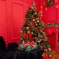 Red Christmas background with a decorated Christmas tree, an armchair, a table with candles and a fireplace Royalty Free Stock Photo