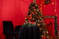 Red Christmas background with a decorated Christmas tree, an armchair, a table with candles and a fireplace Royalty Free Stock Photo