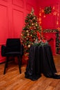 Red Christmas background with a decorated Christmas tree, an armchair, a table with candles and a fireplace Royalty Free Stock Photo