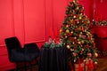 Red Christmas background with a decorated Christmas tree, an armchair, a table with candles and a fireplace Royalty Free Stock Photo