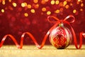 Red Christmas ball on red glitter background with gold lights Royalty Free Stock Photo