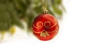 Red Christmas ball with gold decoration hanging from a Christmas tree with blurry background. Ball are partly isolated on white fo Royalty Free Stock Photo