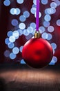 Red christmas ball hanging on a pink ribbon on a wooden table an