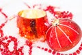 Red Christmas ball on natural white snow with square beads and burning candle in a glass candlestick. Christmas, New year outdoor Royalty Free Stock Photo