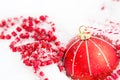 Red Christmas ball on natural white snow with square beads and burning candle in a glass candlestick. Christmas, New year outdoor Royalty Free Stock Photo