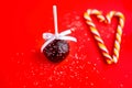 Red Christmas ball with ribbon. Valentine`s Day. Sweets for the holiday. Pops chocolate cake. Coconut flakes on a red background. Royalty Free Stock Photo