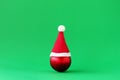 Red Christmas ball with Santa Claus red hat on green background with copy space. Minimal Christmas and New Year concept Royalty Free Stock Photo