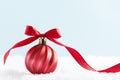 Red christmas ball on snow, with red ribbon on snow isolated, blue background. Winter, christmas greeting card with copy space Royalty Free Stock Photo