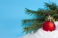 Red Christmas Ball and spruce branch In Snow on a blue background Royalty Free Stock Photo