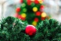 Red Christmas ball in spruce branches close-up on the background of a Christmas tree with red and yellow balls. Royalty Free Stock Photo